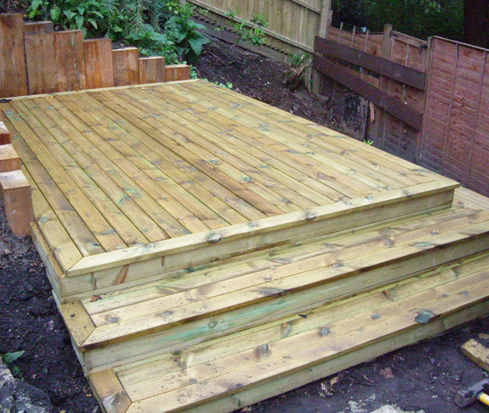Treated softwood decking with new sleeper retaining wall.