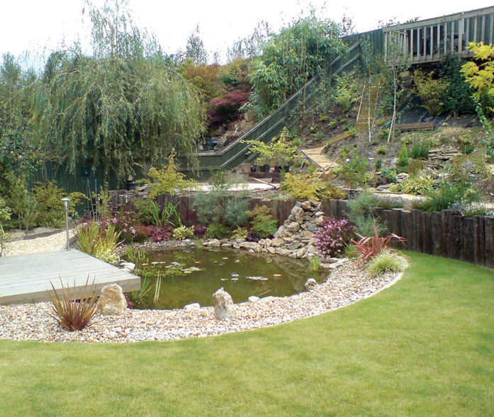Cantilevered deck over pond with rock fall water feature and pebbled margin.