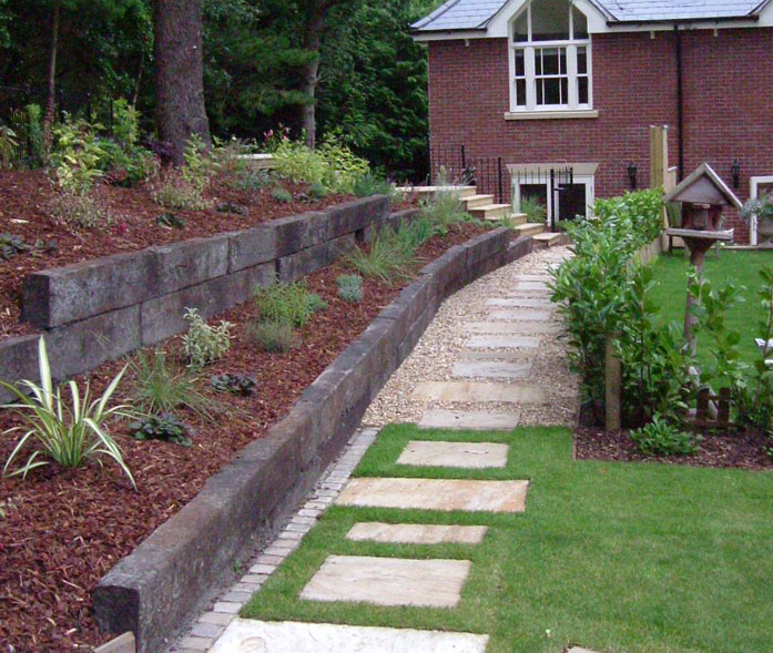 Sandstone stepping stones with railway sleeper retaining walls and pine bark planting beds.