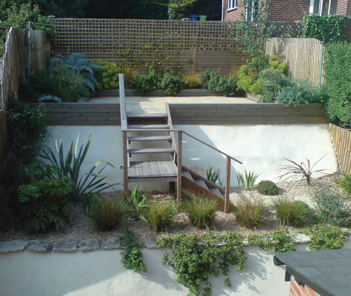 Wooden staircase through planting to raised patio area.